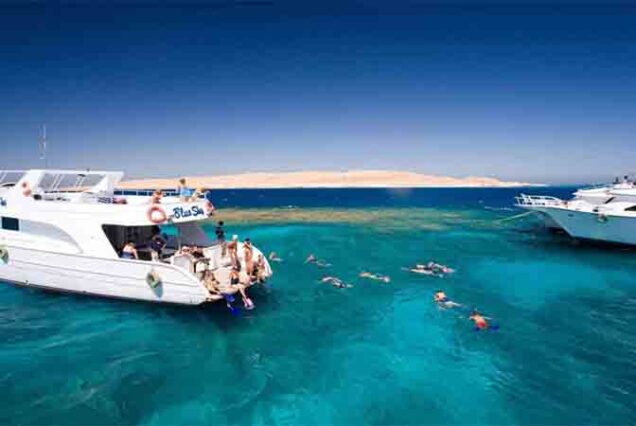Alt Text: Snorkeling w Orange Island Hurghada – turysta pływa nad kolorową rafą koralową z tropikalnymi rybami w Morzu Czerwonym.
