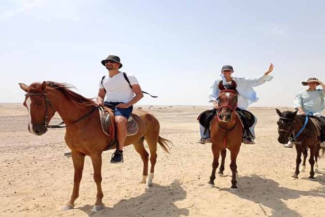 Turysta na spokojnym koniu podczas jazdy konnej po pustyni Synaj w Sharm El Sheikh, panoramiczny widok na góry i złote piaski.